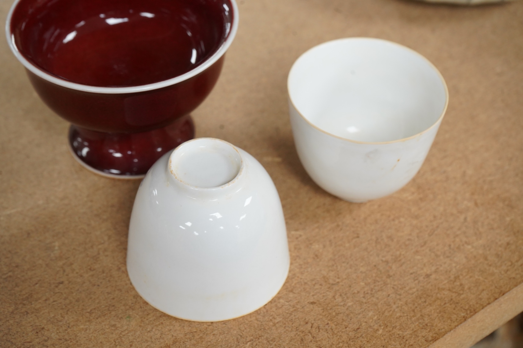 A Chinese red glazed stem cup together with two white glazed tea bowls, tallest 6.5cm